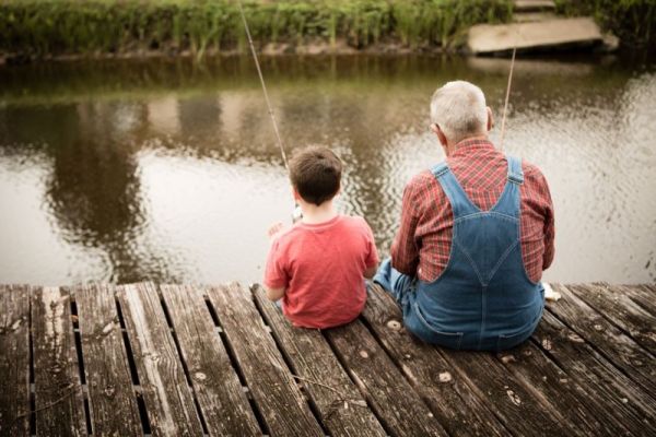 Child and grandfather sitting on a pier and fishing