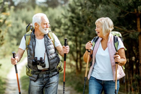 smiling elderly man and woman walking with walking sticks